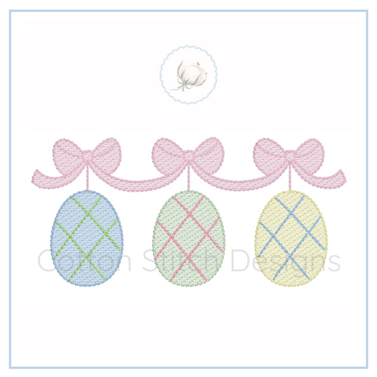 Machine Embroidery design Cotton Stitch Designs Embroidered design of three plaid Easter eggs with pink bows on a white background.