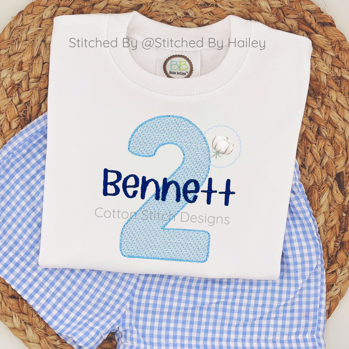 Machine Embroidery design Cotton Stitch Designs White shirt with blue number '2' and name 'Bennett' on a woven surface