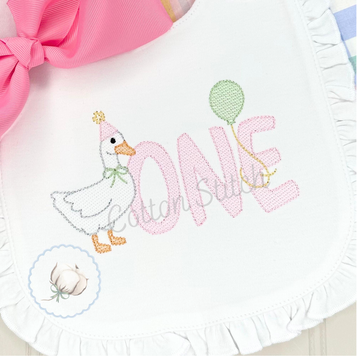 Machine Embroidery design Cotton Stitch Designs Baby bib with duck design and 'ONE' embroidery, featuring a pink bow.