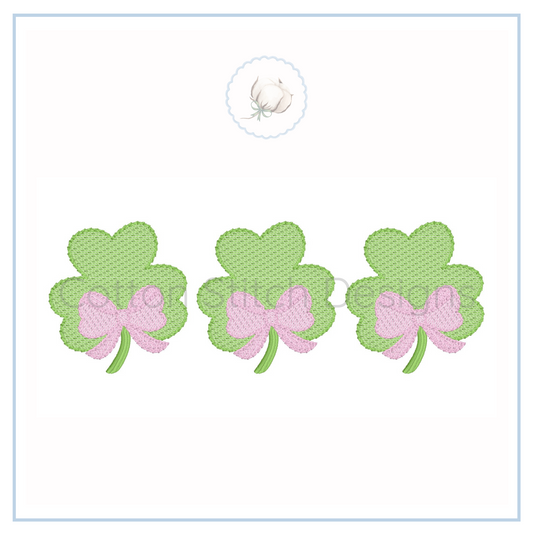 Machine Embroidery design Cotton Stitch Designs Three green shamrock-shaped earrings with pink bows on a white card.