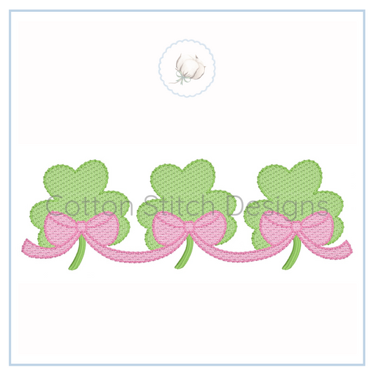 Machine Embroidery design Cotton Stitch Designs Three green shamrocks with pink bows on a white background