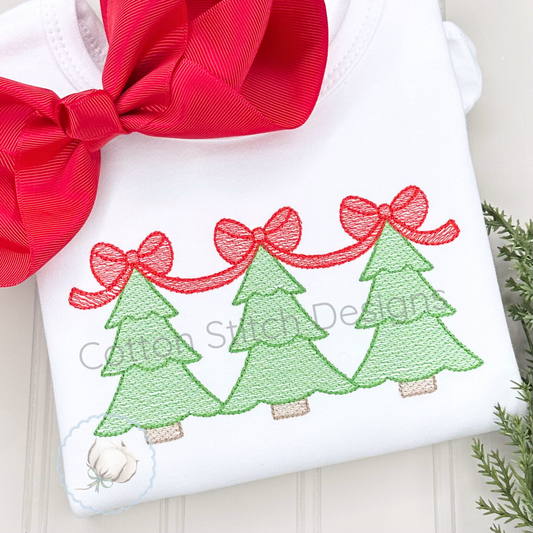 Machine Embroidery design Cotton Stitch Designs White pillow with embroidered green trees and red ribbons, tied with a red bow, on a light wooden surface.